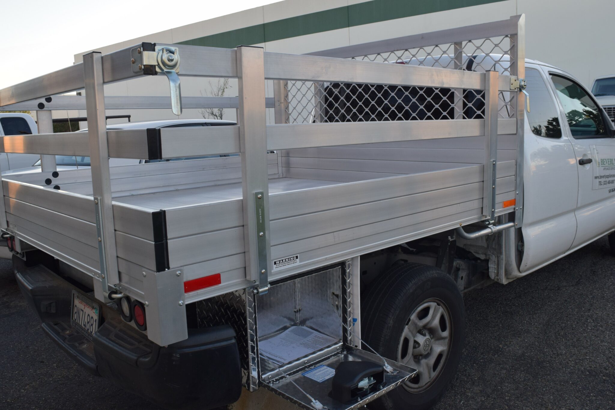 2009 Toyota Tacoma 6’ X 6’6” aluminum flat bed with 22″ fold-down gates, factory bumper retained, and an aluminum tool box 14” X 12” X 18”
