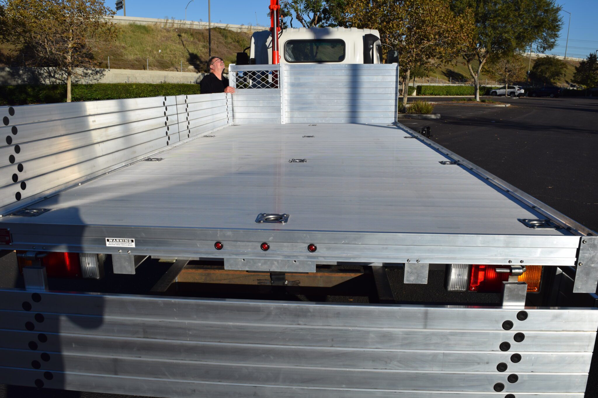 2019 Isuzu NPR 7×16 aluminum flatbed with 15" solid fold-downs and 12 tie-downs