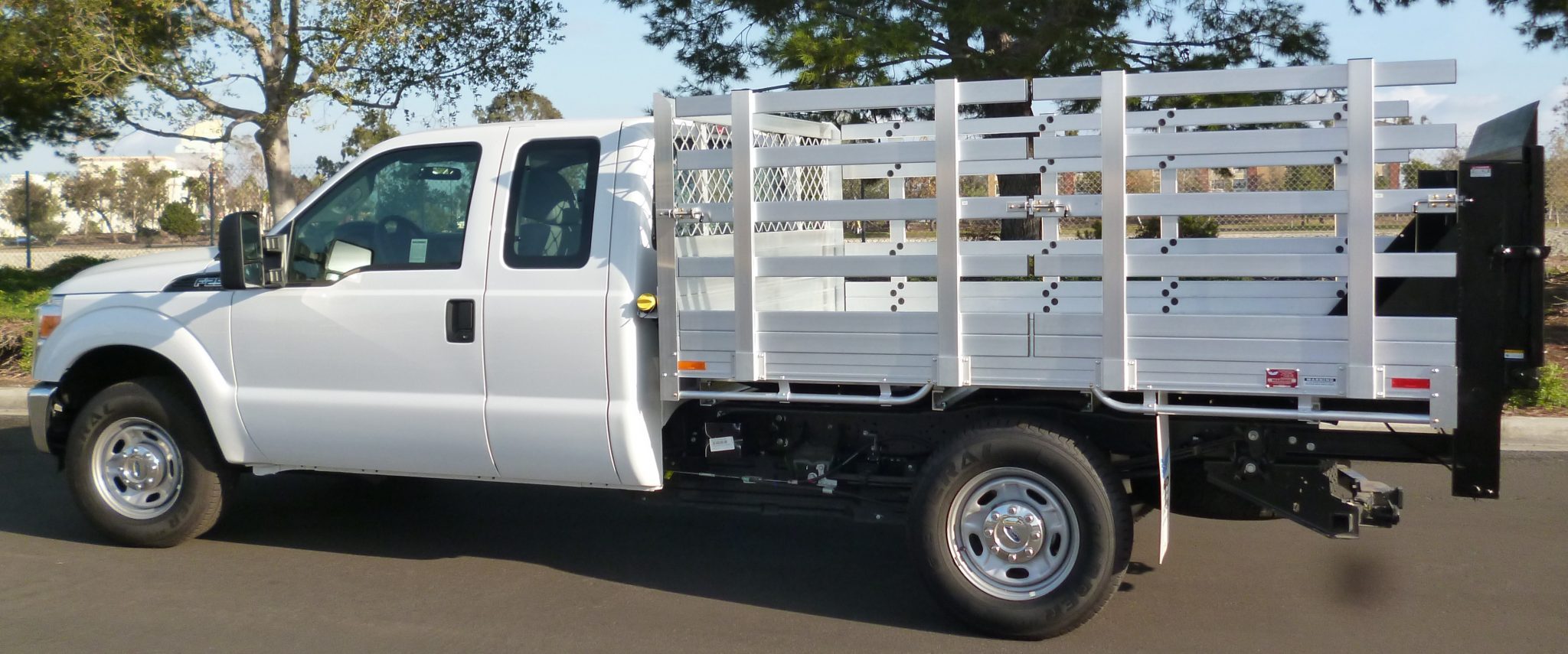 2015 Ford F250 with a 6'6" × 9' AlumBody aluminum stake bed with 38" lift-out stakes and Tommygate lift gate