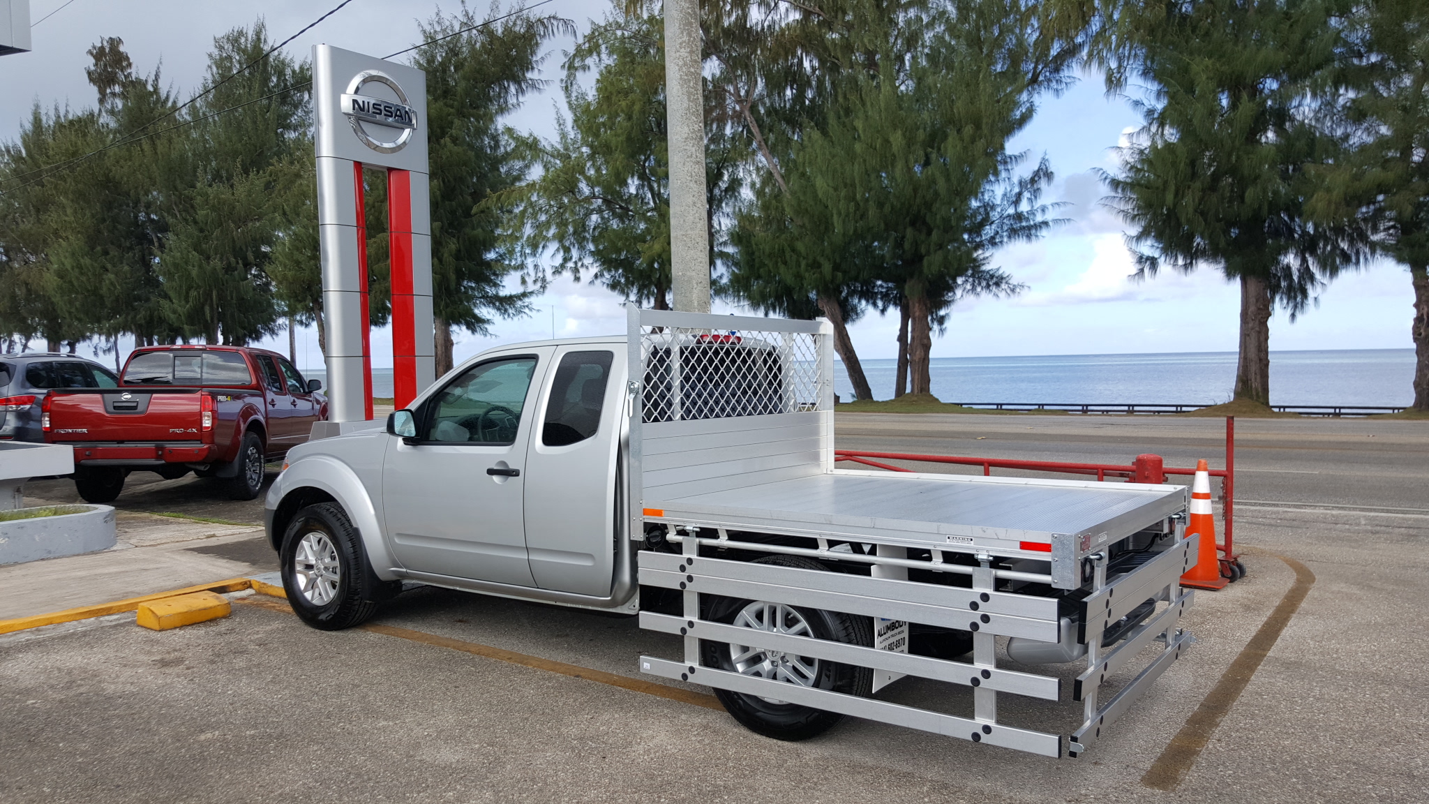 2017 Nissan Frontier with a 6' X 6'6" AlumBody aluminum flat bed with 22" fold down gates using the factory bumper