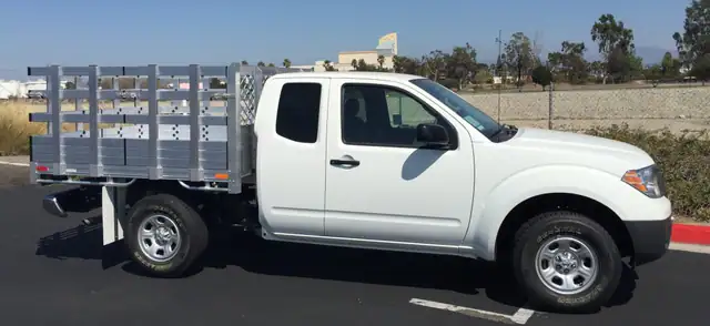2015 Nissan Frontier with a 6' X 6'6" Alumbody aluminum stake bed with 33" lift out stakes using the factory bumper
