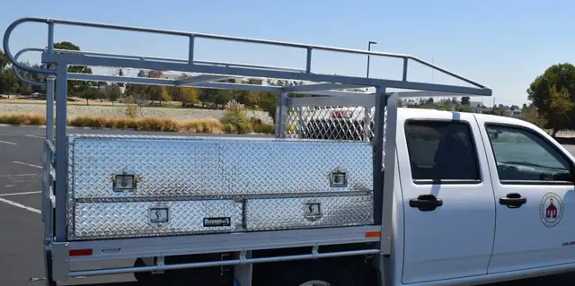 Chevy Colorado with a 6’ X 6’6” Alumbody aluminum flat bed, 2 topsider contractors boxes 21” X 13” X 72”, and ladder rack