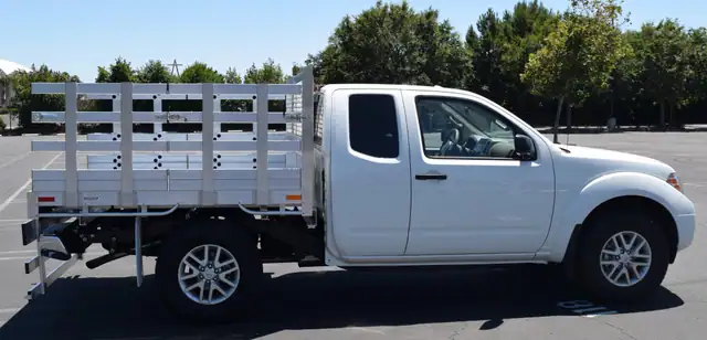 2017 Nissan Frontier with a 6' X 6'6" Alumbody aluminum stake bed with 33" lift out stakes and 22" fold down rear gate using the factory bumper